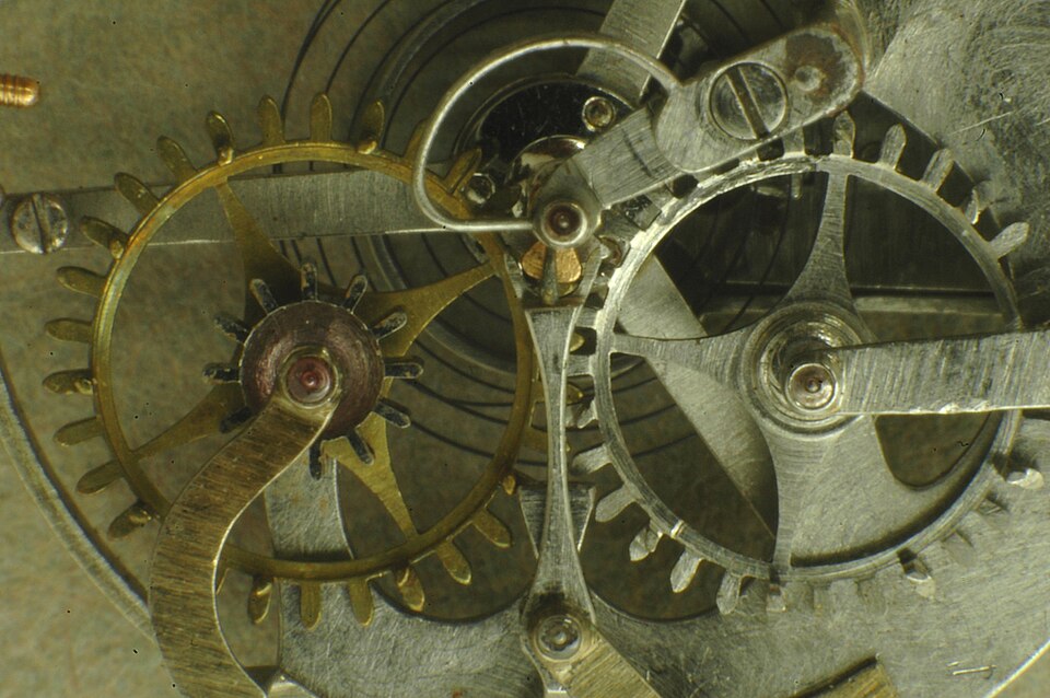 Detail of a Breguet watch movement showing gilt and steel wheels and a jewelled bearing