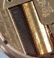 Close-up of the musical comb and pinned cylinder barrel — showing the fine teeth of the comb and the precisely placed pins on the brass cylinder
